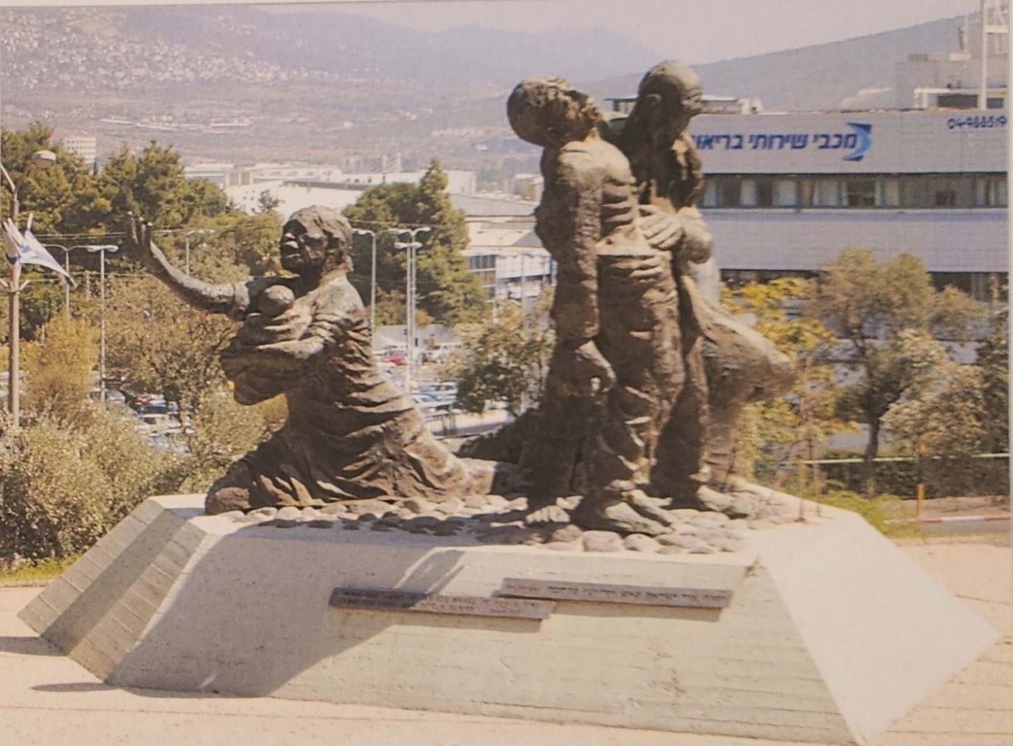 קבוצת פסלי ברונזה על כן בטון בפארק ההנצחה בכרמיאל, על רקע נוף גלילי
